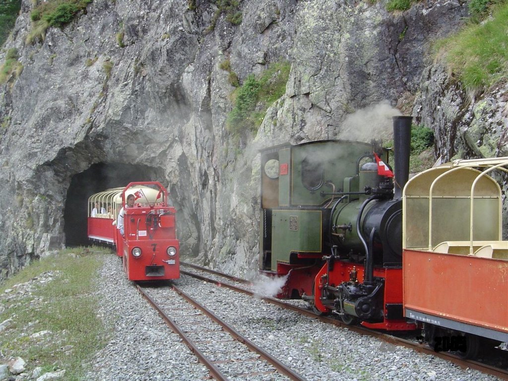 2 ft gauge steam engine  Liseli  (Jung No 1693, built 1911) in service on the high alpin panoramic railway of  Parc d'Attractions du Chatelard (VS)  in Switzerland. In the crossing station No 2. A electric regular train is comming from the station  Pied du Barrage , just leaving tunnel No 3 on its way to the station  Les Montuires . The steam train awaits the crossing. 26 July 2005