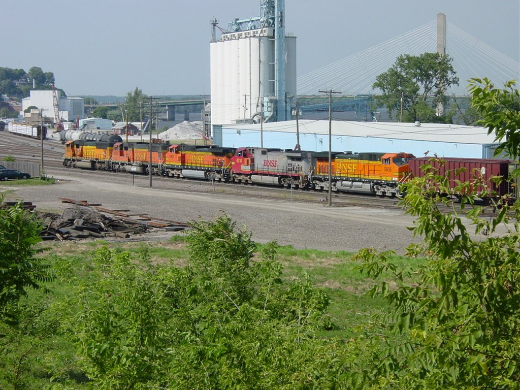 BNSF 8825, 8253, 5457, Santa Fe 4710 & BNSF 5635 pull their train into the Burlington, Iowa yard on 26 July 2003. The blue building is the former Rutherford Potato Co. now leased to a maintenance company. The grain elevator is part of the former ADM complex that exploded in the spring of 1985.