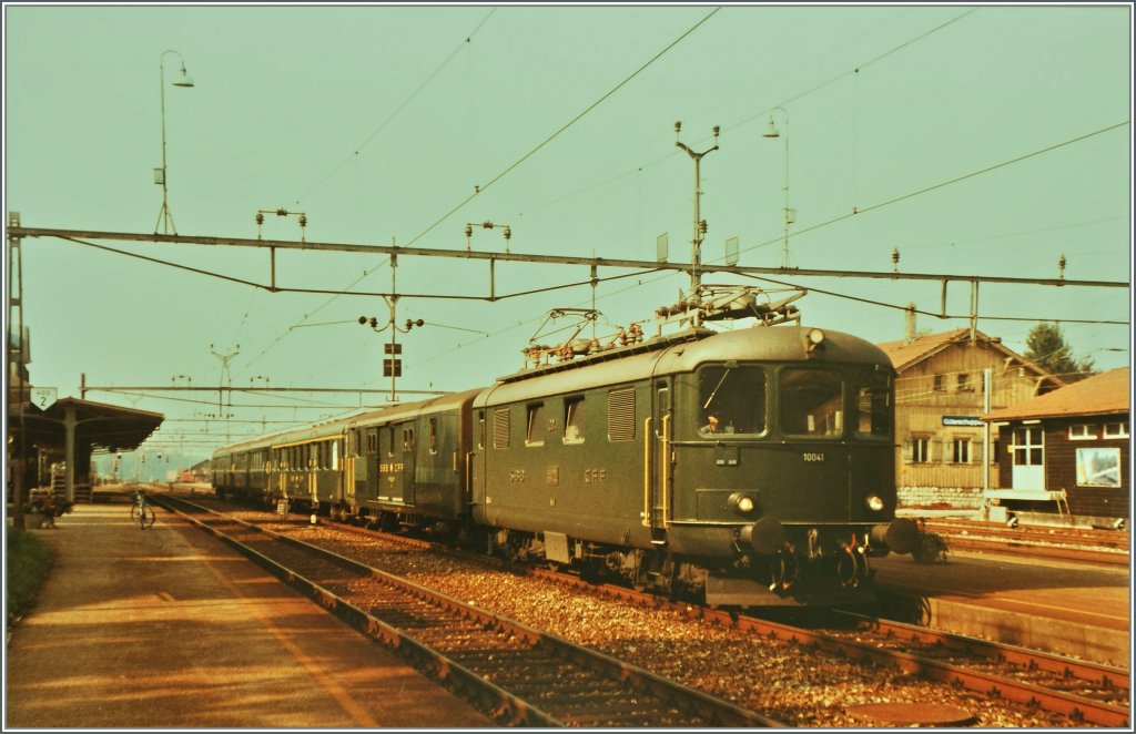 Re 4/4 I 10041 with a fast train to Delemont by the stop in Grenchen Nord.
Summer 1984/pictured picture