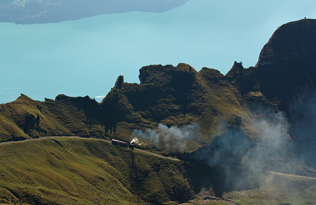 The steamer rises almost effortlessly, but smoking up the mountain. The coal-fired BRB 6 runs on 01.10.2011 to the Brienzer Rothorn up here at the crossing point the Oberstaffel(1828 m above sea level). In the background is Lake Brienz.