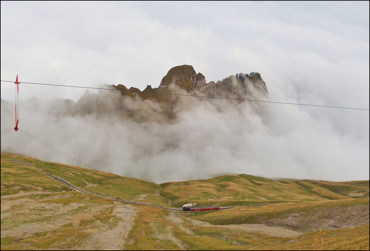 . A small steam train is running on the beautiful track of Brienz Rothorn Bahn, while the fog is arriving on the summit of Rothorn on September 19th, 2013.