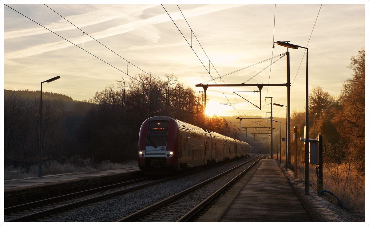 . While the sun is rising on the cold December 16th, 2013 morning, the IR 3708 Luxembourg City - Troisvierges is entering into the station of Wilwerwiltz.