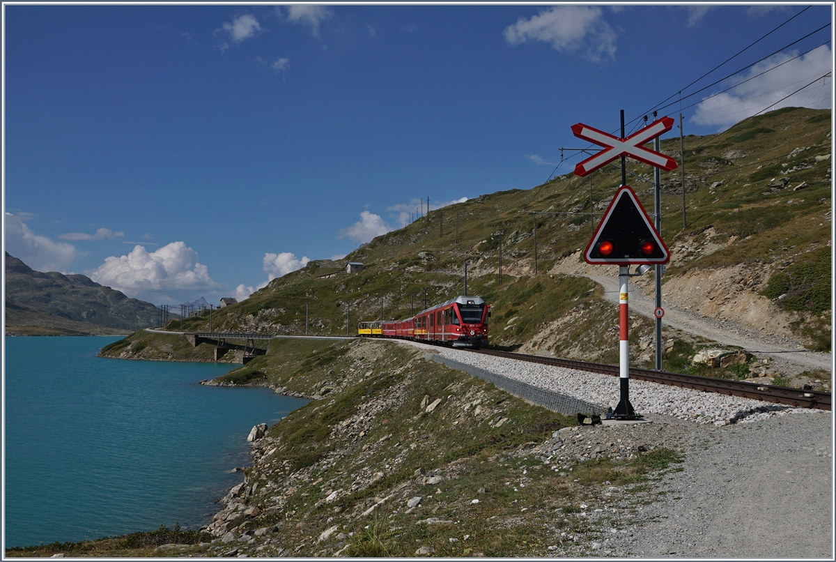 A Bernina Bahn local service on the way from St Moritz to Tirano by the Lago Bianco near the Bernina Osppizio.