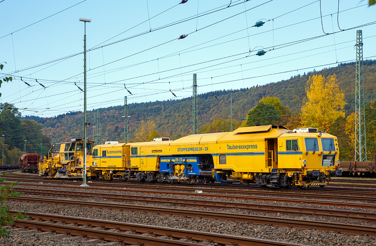 
STRABAG  Tauberexxpress  a Plasser & Theurer Track Tamping Machine CSM 09 – 3X (PL), standing on 23.10.2016 in Betzdorf/Sieg (Germany). 

Equipment:
- Proportional parallel levelling system
- Single axis: 3-point alignment system with laser control
- Combined height-directional laser (KHR)
- Automated control computer ALC with additional USB port, WIN version, disk and CD drives
- Data processing possible for all EM-SAT data
- Digital 8-channel recorder, incl. record function, DAR graph and DAR control (software for operating and displaying the MKS and its data)
- Mephisto fixed point laser measuring  instrument Front compactors for compacting the ballast bed
- Sound-insulated operator cab
- 2 x three-sleeper tamping units, tamping performance of up to 2,200 m/h
- Laser wagon for accommodating the laser transmitter, self-propelled and with integrated surveying wheel
- Highly wear-resistant tamping tines
- Polish safety equipment for self-propelled travel on PKP       


Technical data: 
Manufacturer: Plasser & Theurer
Year of construction: 2001
VDM no.: 99 80 9121 004-2 D-BRS
Engine:  Caterpillar E3412 E/DITA 12 cylinder water-cooled at 2100 rpm
Power:  704  kW
Max. self-propelled speed: 100 km/h
Max. speed in haul drive: 100 km/h
Self-propelled direction:  both ways
Number of axles: 7
Deadman‘s control system: yes
IATC:  yes
Train radio communication analog/digital:yes
Working speed: up to 2,200 m/h
Operating principle:  three sleeper or one sleeper
Min. radius when working: 200 m
Min. radius when travelling: 150 m

Vehicle: 
Licenced: in acc. with EBA/DB AG Guidelines Section 32
Rail gauge:  1.435 mm
Dead weight: 100.0 t
Height:  3,900  mm
Width: 3,000  mm
Length over buffers: 29,900 mm 

And behind the Plasser & Theurer Ballast Distributing and Profiling Machine SSP 110 SW (heavy vehicle no. 99 80 9425 014-4 D-STRA) of the STRABAG