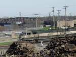 SD 70 Burlington Northern 9709 & 9689 pull an empty coal train across the Mississippi River and into the yard at Burlington, Iowa on 9 Apr 2005. The bridge swing span and tender shack are visible just above the lok cab. The other building is the sewage treatment plant.