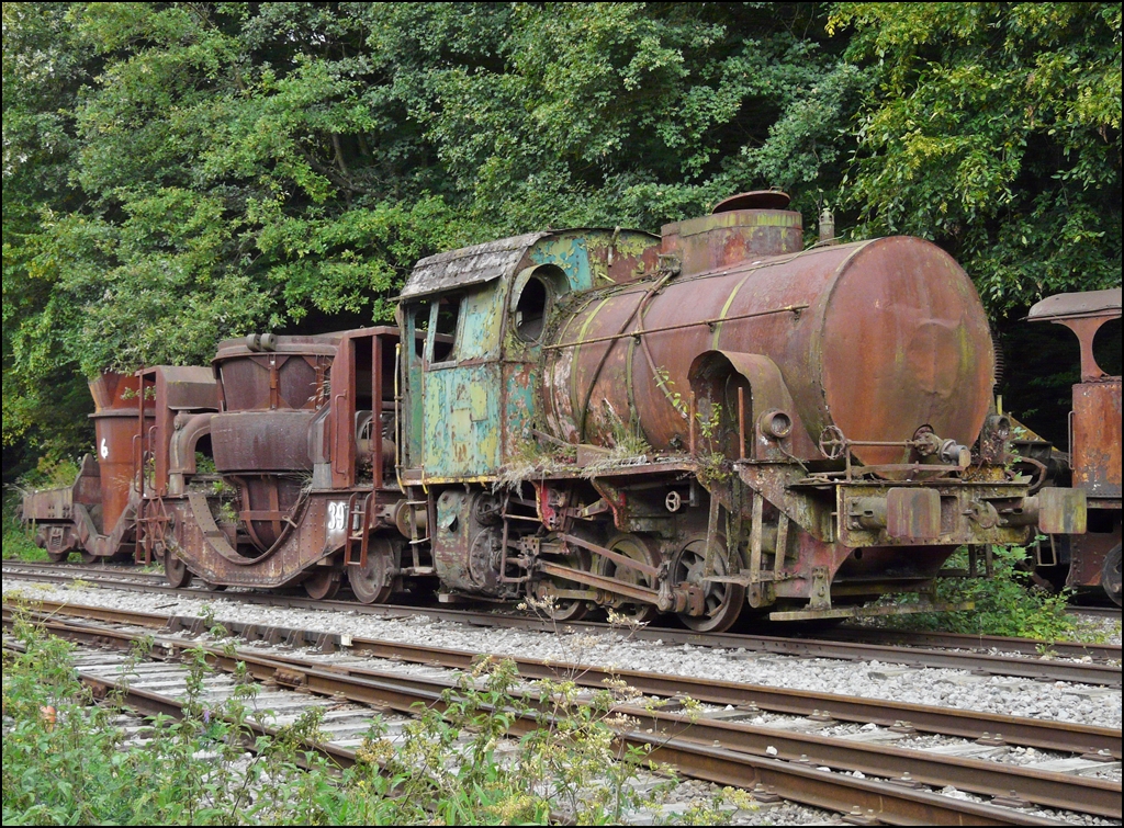 . Locomotive without boiler N V 12 with 3 axles, belonging to ARBED Dudelange. Built in 1956 by Jung-Kirchen Jungenthal/Sieg under the number 12513. 
Type designation by the manufacturer:  Felix . 
Power 250 hp, weight 39t.

Fond de Gras, September 13th, 2009.

The advantage of this type of locomotive it is very simple and robust, the most complicated of a normal locomotive (with boiler) is the boiler. It was so cheap to acquire and in maintenance. His conduct is easy and does not require highly skilled personnel. The exhaust of the locomotive is composed of only water vapor, gas combustion and smoke. It can therefore operate safely in areas covered and within the halls of manufacture. The disadvantage is of course to have a limited range and require a distribution network Steam. The latter was not available for all kinds of applications in the steel mills. 
