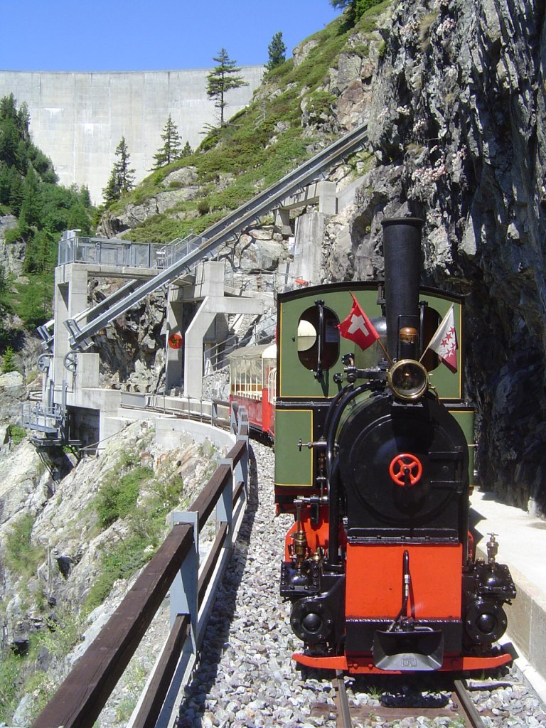 2 ft gauge steam engine  Liseli  (Jung No 1693, built 1911) in service on the high alpin panoramic railway of  Parc d'Attractions du Chatelard (VS)  in Switzerland.
In the station  Pied du Barrage  (translated = Foot of the Dam) on 1'800 metres about sea level. Behind the steep climbing rails of  Minifunic  and to the horizon is to see the immense dam of Lake Emosson. Special picture was taken unter security surveillance of railway employees. 03 July 2011