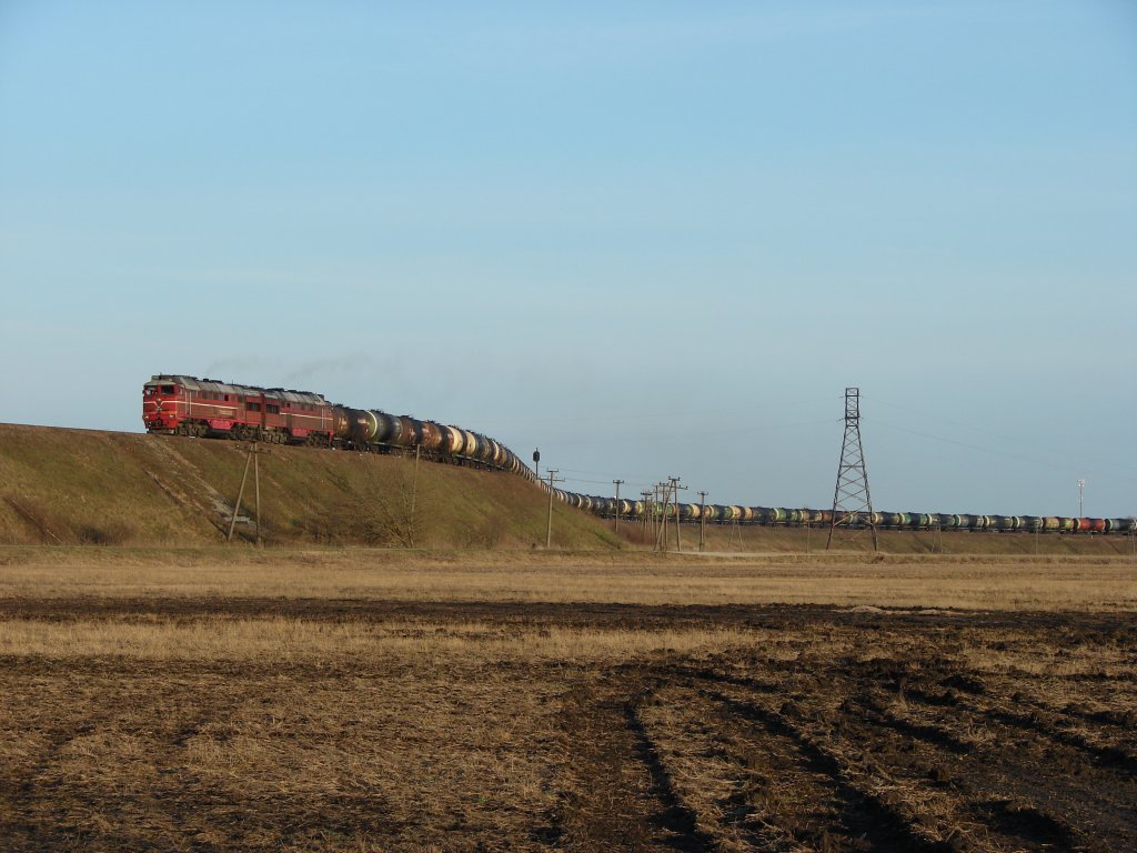 a 2T3116 double-diesel winds its way up to the bridge over the road Tallinn - Narva with a loaded oil train