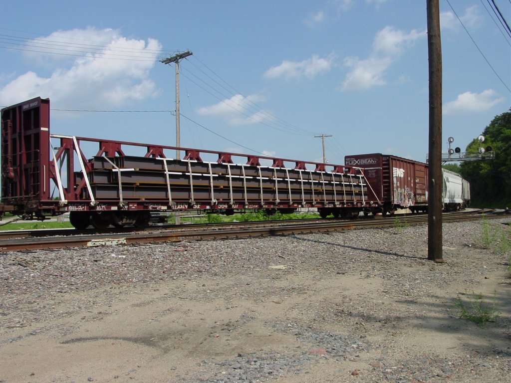 A BNSF FLEX BEAM car hauls a load of steel I-beams around the curve and onto the Mississippi River bridge. 30 July 2003.