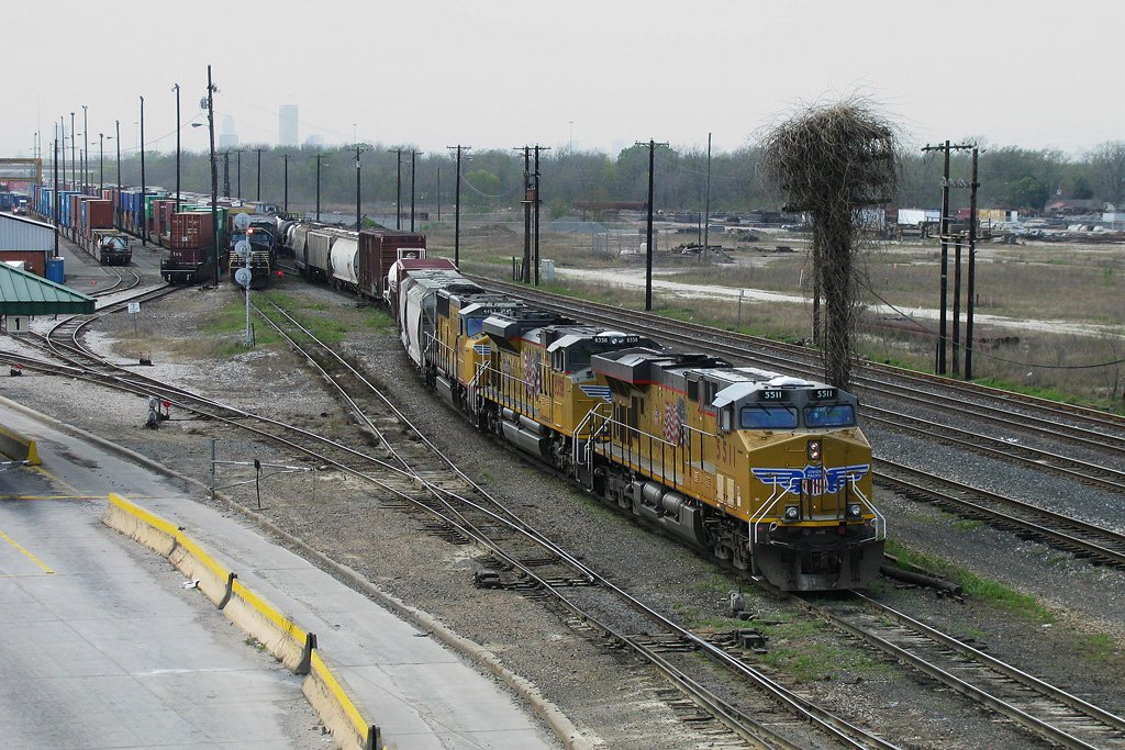 A freight train of the Union Pacific with three engines of different types is arriving in a yard in Houston Texas. The first one is a “C45ACCTE” with the number 5511, the second one is a “SD70ACe” (8358) and the third one  is a “SD70M” and has the number 4462. 16.03.2008.