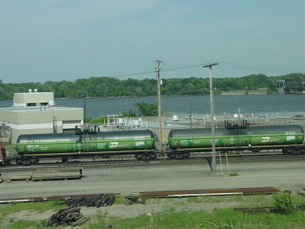 A pair of Burlington Northern tank cars rolls thru the Burlington, Iowa yard on 26 July 2003. These units were once part of a test in the 1980s when the railroad tried using propane as a fuel instead of diesel. These tank cars were set between locomotives during the tests. I worked at Caterpillar Engine Division at the time. The test did not go well and was scrapped, so was my job soon after.