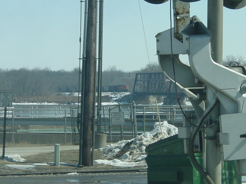 An eastbound BNSF -9 (?) pushes its loaded coal train off the Mississippi River bridge and onto the floodplains of western Illinois. The crossing arm in the forground is the South Street crossing in Burlington, Iowa. 3 Mar 2010.