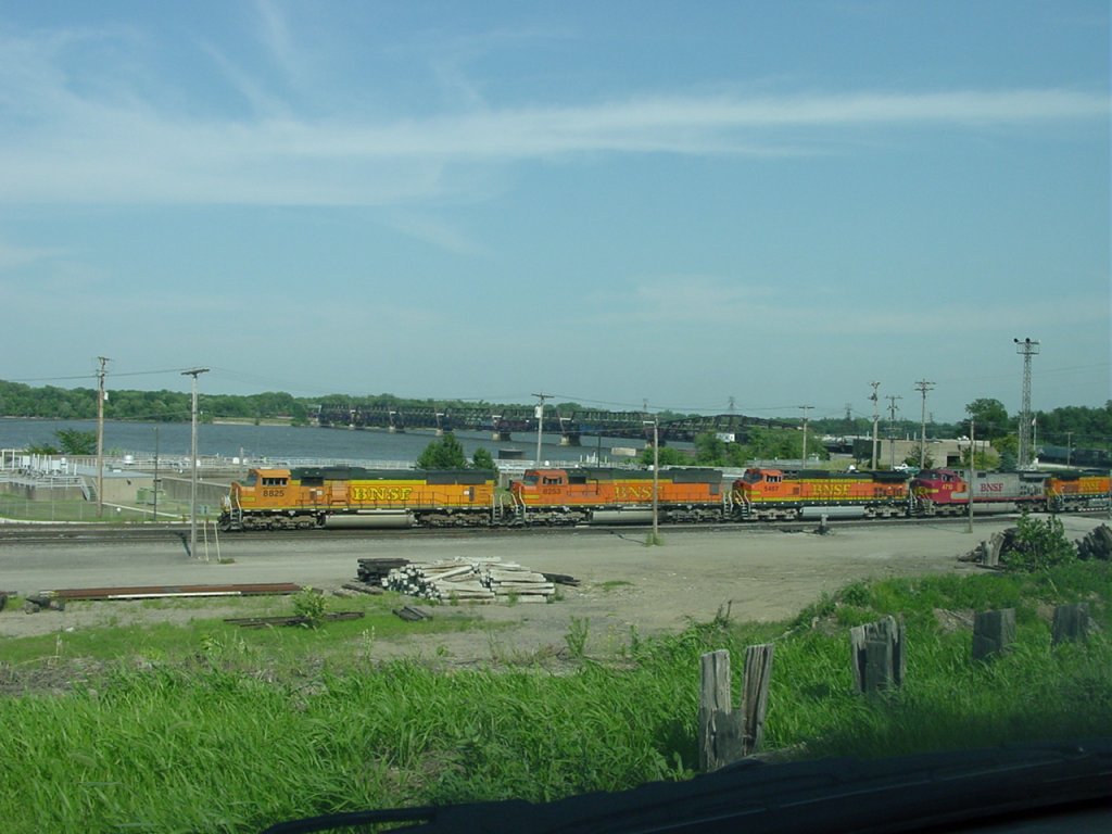 BNSF 8825, 8253, 5457, Santa Fe 4710 & BNSF 5635 lead a mixed freight into the Burlington, Iowa yard on 26 July 2003. The Mississippi River bridge is visible with the tail end of the train still in Illinois.