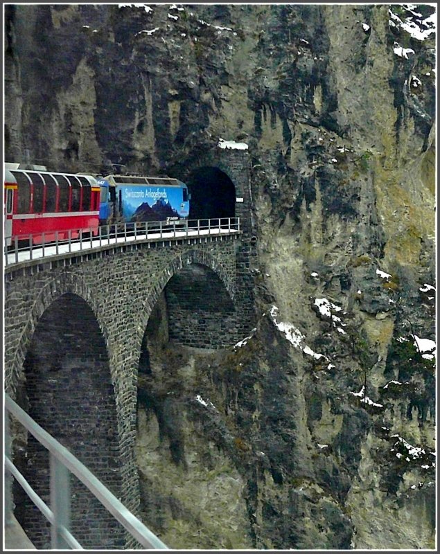 Ge 4/4 III 647 with the Bernina Express is crossing the 450 foot long  Landwasser  viaduct and will enter soon into the more than 200 yard long  Landwasser  tunnel on December 24th, 2009.
