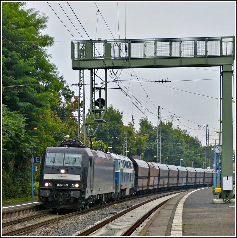 MRCE 185 565-9 is hauling the NIAG 216 111-5 and goods wagons through the station of Remagen on July 28th, 2012.