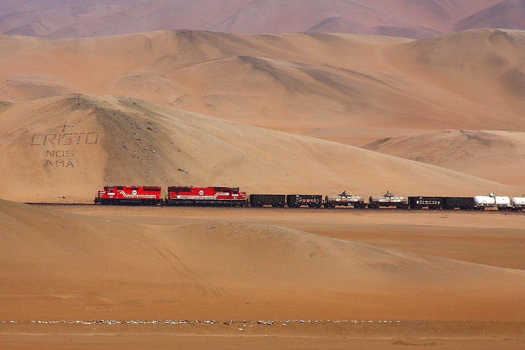 SPCC 32 & 61 ( GP40 + SD70 ) pass by a hillside writing -  Jesus loves us  - at km 38 above Ilo in Southern Peru