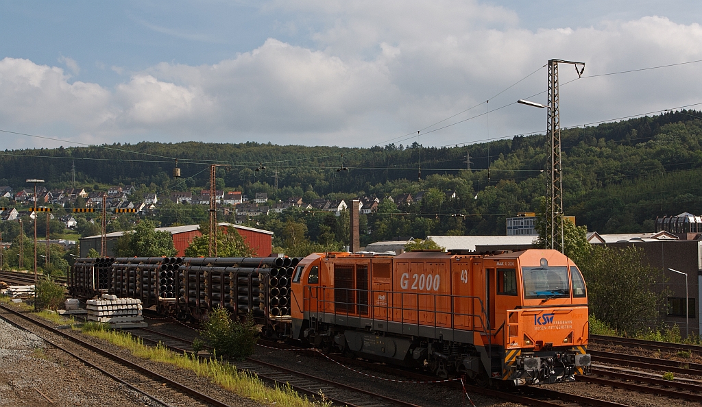 The G 2000 (Lok 43) of the Kreisbahn Siegen-Wittgenstein (KSW) with steel tube freight train on 29.7.2011 in Siegen (Kaan-Marienborn). The tubes were being picked up from the tubes factory, and transported (via Siegen) to Kreuztal onto DB Schenker, for further transport handed.