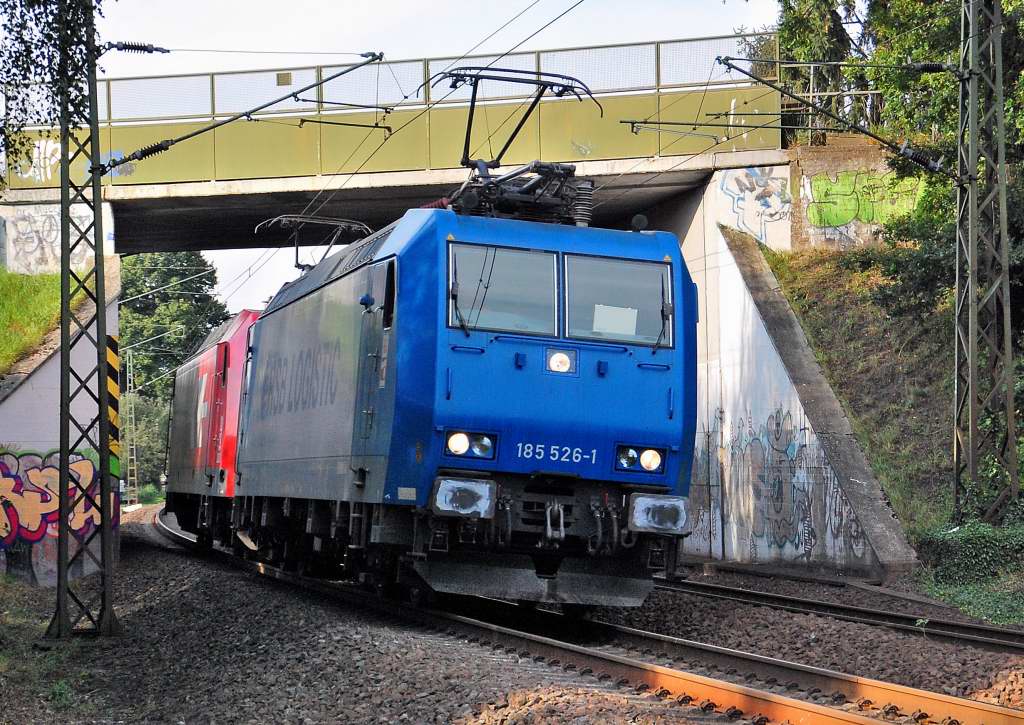 Two electrical locomotives on there way to cologne been seen here in the city of Ostherath. They passing the curve near the railroadcrossing Viehgasse.Those locomotives are the class 185 526-1 and the class 145 015 cl from the HGK Habour and Goods Cologne. Septembre second of 2012