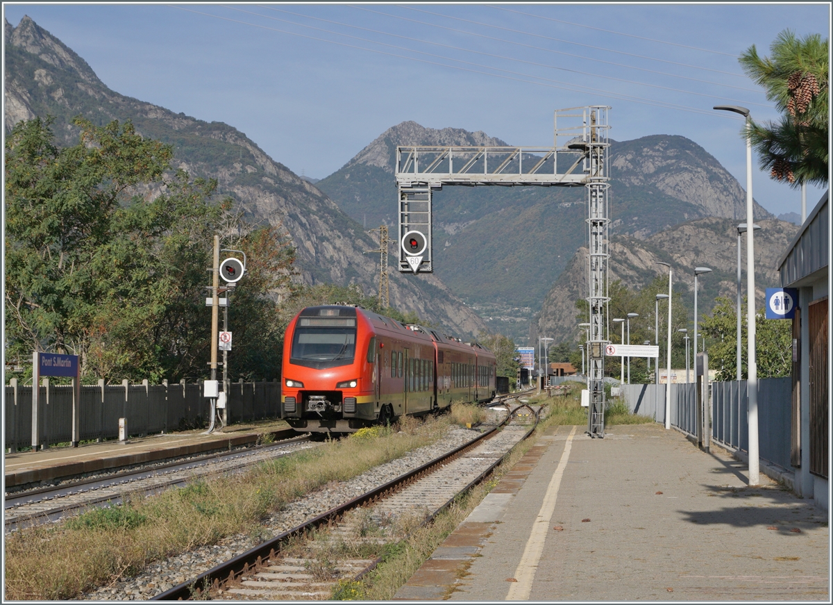 A red FS regional train and the station is not called  Ponte di San Martino  but  Pont S. Martin  - therefore this picture comes from the Aosta Valley. The view looks north from the southernmost train station and shows the FS Trenitalia BUM BTR 813 001 traveling as RV VdA 2718 from Aosta to Torino Porta Nuova. It will soon leave the Aosta Valley after its stop in Pont S.Martin and the subsequent onward journey. October 12, 2023