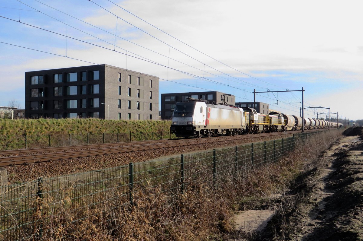 Akiem/Lineas 186 387 and two SNCB Class 77 haul a diverted dolime train through Tilburg-Reesghof on 21 February 2021.