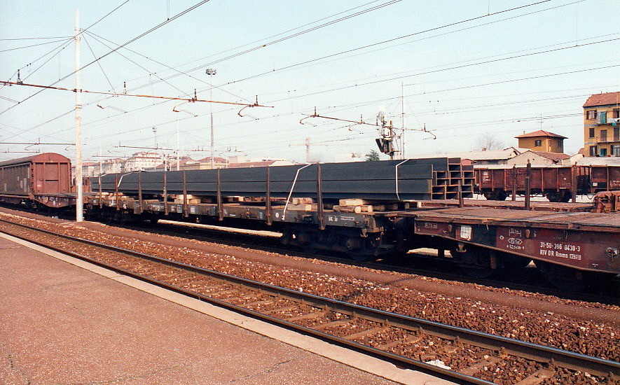 Flat Wagon Rs of the DB loaded with overhanging steel I-beams, passing through Milano in March 1995 together with 2 idler flats  