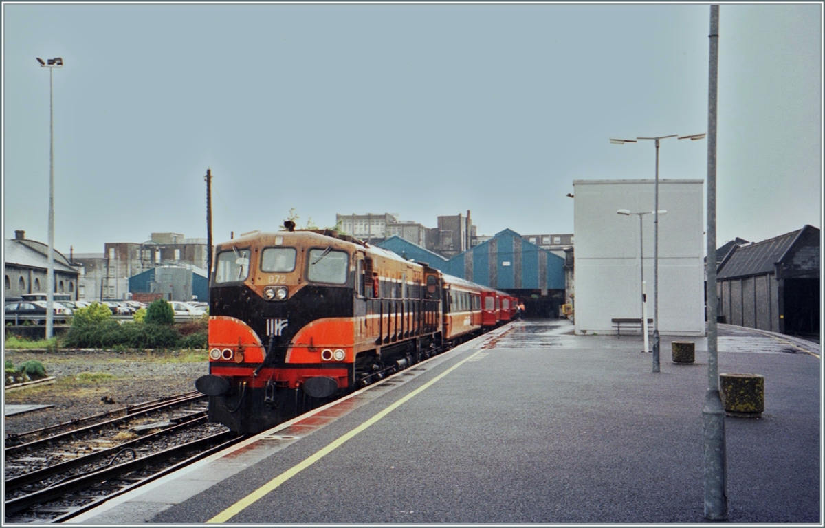 On a rainy day in Galway, the CIE (Iarnród Éireann) diesel locomotive CC 072 is waiting at the Ceannt Station Galway / Stásiún Uí Ceannt with an Intercity to depart (Dublin) Heuston.

Analog image from June 2001