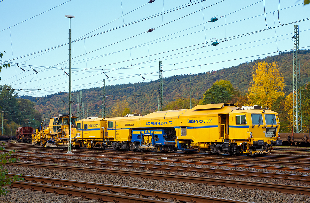 
STRABAG  Tauberexxpress  a Plasser & Theurer Track Tamping Machine CSM 09 – 3X (PL), standing on 23.10.2016 in Betzdorf/Sieg (Germany). 

Equipment:
- Proportional parallel levelling system
- Single axis: 3-point alignment system with laser control
- Combined height-directional laser (KHR)
- Automated control computer ALC with additional USB port, WIN version, disk and CD drives
- Data processing possible for all EM-SAT data
- Digital 8-channel recorder, incl. record function, DAR graph and DAR control (software for operating and displaying the MKS and its data)
- Mephisto fixed point laser measuring  instrument Front compactors for compacting the ballast bed
- Sound-insulated operator cab
- 2 x three-sleeper tamping units, tamping performance of up to 2,200 m/h
- Laser wagon for accommodating the laser transmitter, self-propelled and with integrated surveying wheel
- Highly wear-resistant tamping tines
- Polish safety equipment for self-propelled travel on PKP       


Technical data: 
Manufacturer: Plasser & Theurer
Year of construction: 2001
VDM no.: 99 80 9121 004-2 D-BRS
Engine:  Caterpillar E3412 E/DITA 12 cylinder water-cooled at 2100 rpm
Power:  704  kW
Max. self-propelled speed: 100 km/h
Max. speed in haul drive: 100 km/h
Self-propelled direction:  both ways
Number of axles: 7
Deadman‘s control system: yes
IATC:  yes
Train radio communication analog/digital:yes
Working speed: up to 2,200 m/h
Operating principle:  three sleeper or one sleeper
Min. radius when working: 200 m
Min. radius when travelling: 150 m

Vehicle: 
Licenced: in acc. with EBA/DB AG Guidelines Section 32
Rail gauge:  1.435 mm
Dead weight: 100.0 t
Height:  3,900  mm
Width: 3,000  mm
Length over buffers: 29,900 mm 

And behind the Plasser & Theurer Ballast Distributing and Profiling Machine SSP 110 SW (heavy vehicle no. 99 80 9425 014-4 D-STRA) of the STRABAG