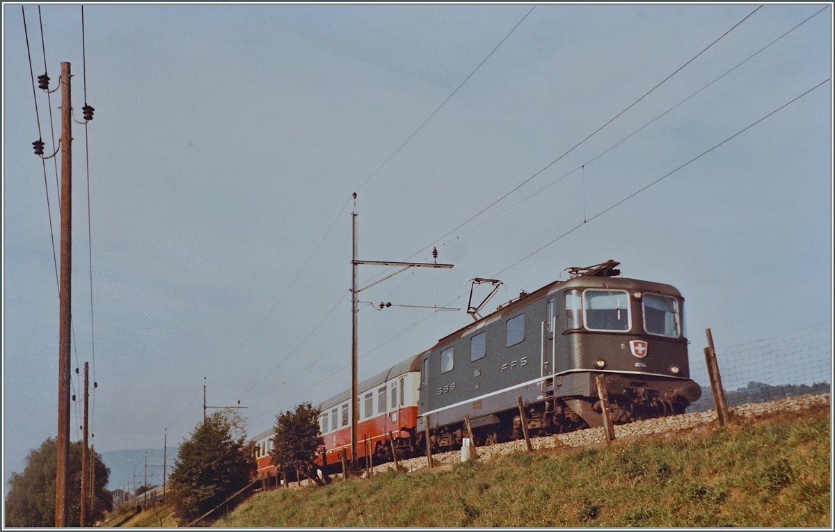 The SBB Re 4/4 II 11244 with the IC Mont Blanc (Cerbère) - Genève - Hamburg between Lengnau and Grenchen Nord. 

analog picture / Sept. 1984