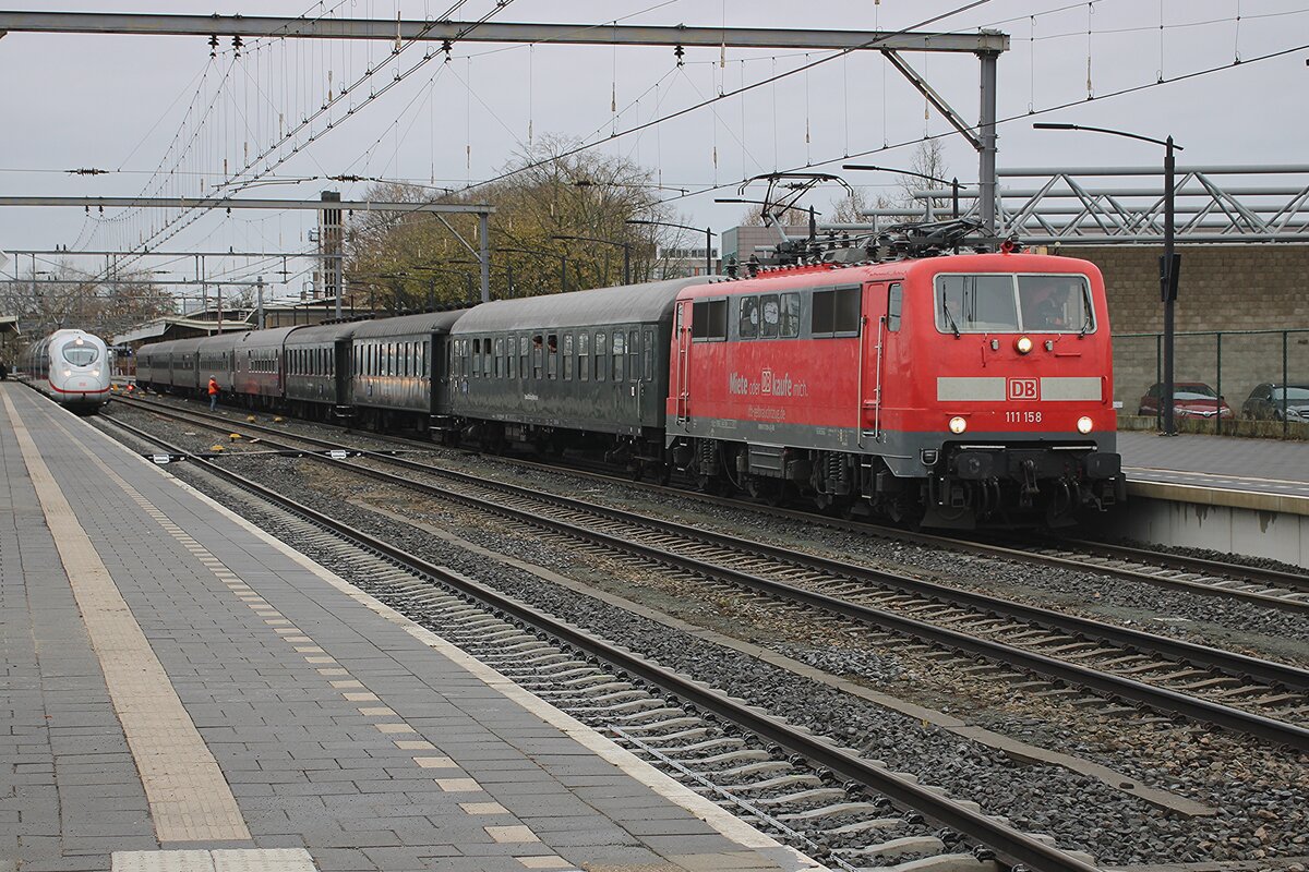 Time warp? On 6 December 2025 DB 111 158 stands at Venlo with an extra train to Bonn that constists of some DB coahces from the 1960s and 1970s, but also one or two coaches from the 1930s. The much more modern ICE Class 407 awaits departure on track 3 in the back ground.