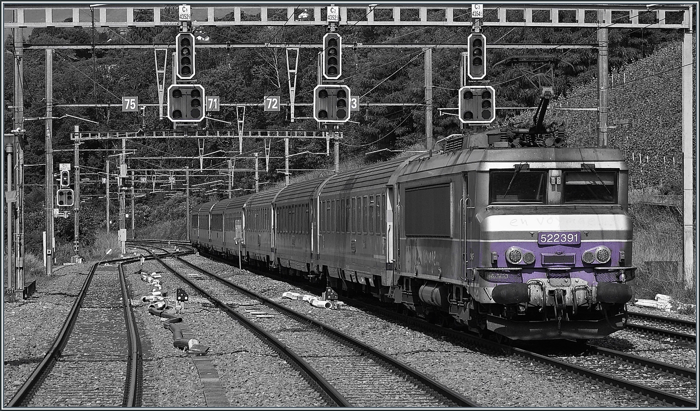 Une image en noir et blanc colorée : la SNCF BB 22391 « Nez cassé » circule avec son TER 96634 à travers la gare de La Plaine et atteindra bientôt la France. Les anciens mâts de caténaire en courant continu, équipés en retrofit avec du matériel de ligne aérienne SBB, sont toujours en place et alimentent désormais la ligne en courant alternatif SNCF à 25 000 volts 50 hertz. Mais comme le suggère l'extrémité gauche de l'image, d'importants travaux de reconstruction sont prévus pour la gare, qui présentera donc probablement bientôt un aspect différent. En bas à gauche de l'image, un morceau de butoir « perturbe » la vue mais montre que j'ai pris la photo depuis le quai. Le TER effectue le trajet de Genève (départ 9h57) à Valence (arrivée 13h13). 1er juin 2026