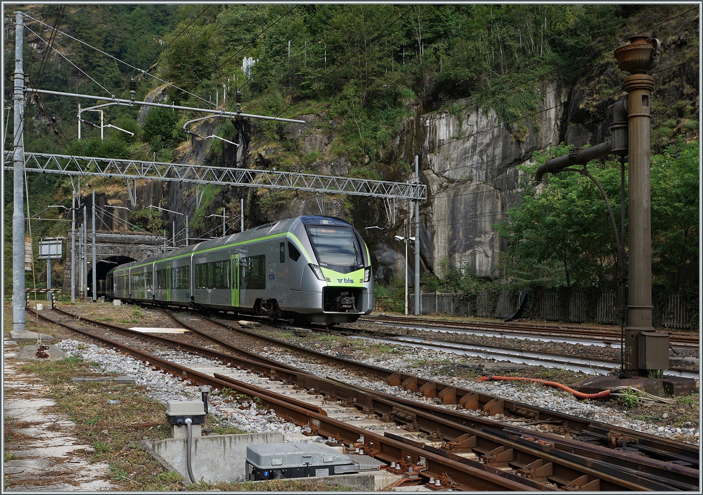 The BLS RABe 528 103 arrives at the station of Iselle di Trasquera. On the right side of the image, a decommissioned water crane can be seen.  
August 17, 2025