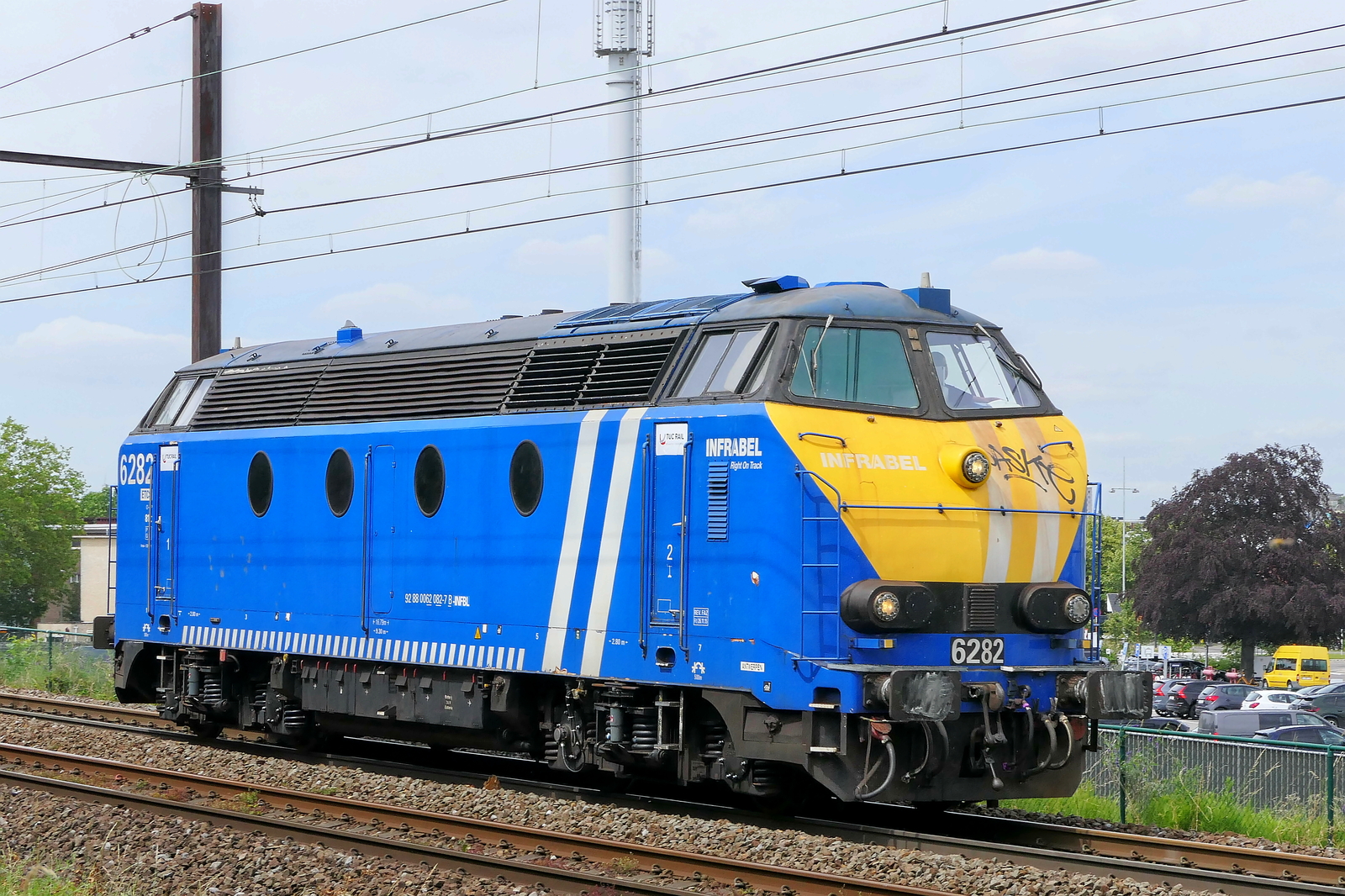 The Infrabel 6282 on route from the port of Antwerp. BN Brugge HLD 62 build in 1966 with construction N� 212 182.  NMBS Class 62: between 1961 and 1966 136 of these diesel locomotives were build by BN Brugge. Numbers: 6201 to 6333 and 6391 to 6393. Max speed: 120km/h. Power: 1030kW. 48 are still in service at Infrabel. The white building on the right site of the photo is the terminal of Antwerp Airport. Line 27A at Antwerp Airport. 15-06-2026 