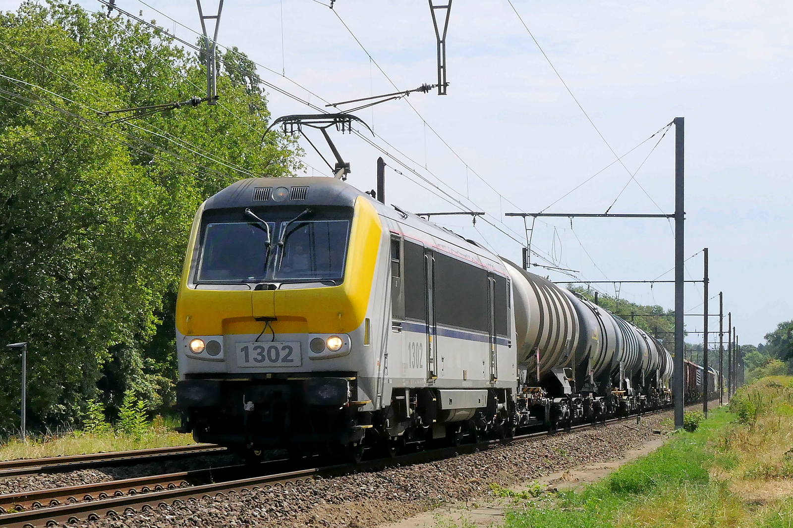 The Lineas 1302 with a mixed train on route to the port of Antwerp.  NMBS serie 13 build in 1998 with construction N� 1302. NMBS Class 13: between 1997 and 2001  80 of these locomotives were build by Bombardier Brugge. Concept and parts from Alstom Belfort. Original NMBS numbers: 1301 to 1360, CFL numbers: 3001 to 3020. Max speed: 200km/h. Power: 5200kW. Power supply: 3000V and 25kV.  Numbers 1301 to 1345 are in service at Lineas, numbers 1346 to 1360 are in service at the NMBS. Line 27A at Antwerp Airport. 04-08-2026