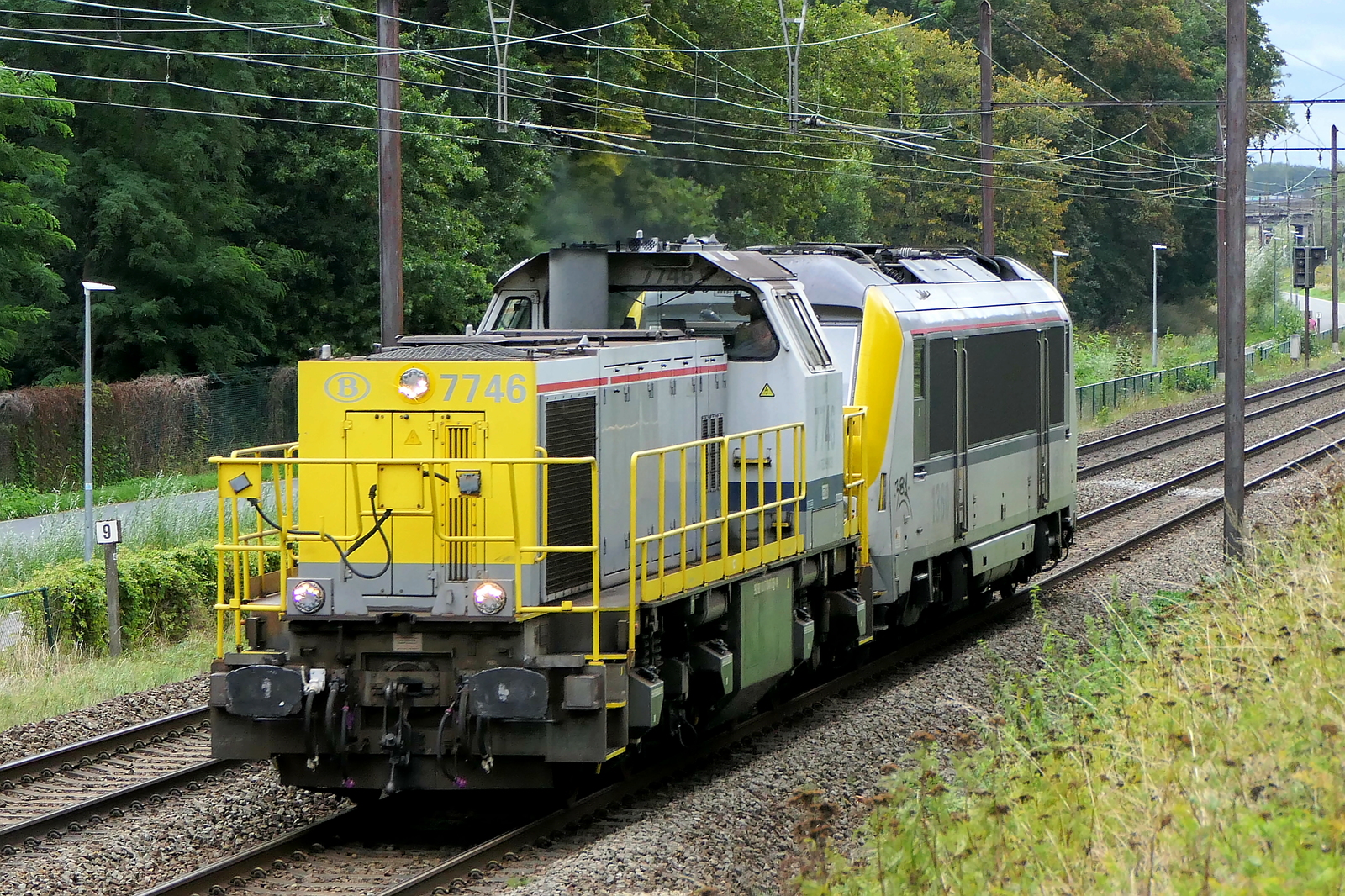The NMBS 7746 (name: Lima) towing the NMBS 1360 to the service depot in the port of Antwerp. Siemens-Vossloh NMBS serie 77-78 build in 2001 with construction N� 1000963. NMBS Class 77: between 1999 and 2005  170 of these diesel locomotives were build by Siemens-Vossloh. Numbers: 7701 to 7870.  Max speed: 100km/h. Power: 1150kW.  110 are in service at Lineas, 37 are in service at the NMBS, 23 are in service at Infrabel, BLS Cargo Nord have 3, Certus Rail have 3 in service.  Line 27A at Antwerp Airport. 03-09-2026