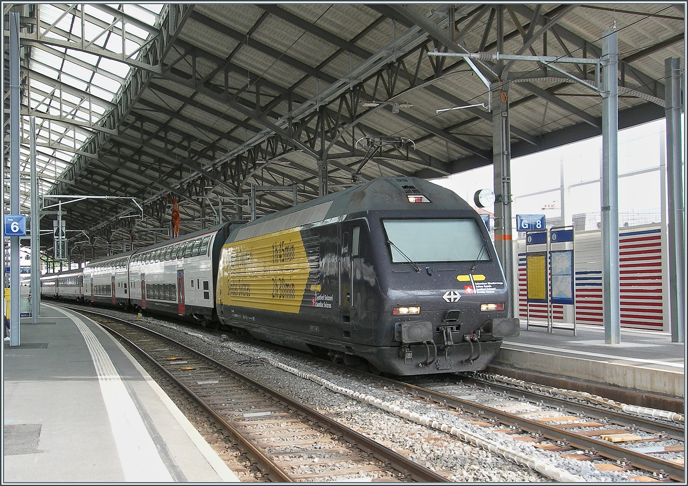 The SBB Re 460 028 (Re 460 91 85 4 460 028-4 CH-SBB) features the attractive advertising decoration    Schweizer Wanderwege / Suisse Rando / Sentieri Svizzeri / Sendas Svizras . although the locomotive probably looks even better with the yellow front.  
The SBB Re 460 028 was photographed at the stop in Lausanne with the IR 95 1724 from Brig to Nyon.  

August 14, 2026