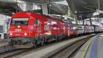 Diesel locomotive 2016 025 stands with 2 passenger cars, then the electric locomotive 1144 236 with additional passenger cars is attached, on the platform at the station in Vienna.