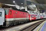 Electric locomotive 1144 236 coupled between passenger cars at the platform in Vienna station.