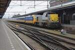 SNCB 7718 stands at Roosendaal with a stranded fast train on 17 March 2025.