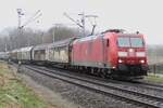 In murky weather conditions, 185 197 hauls a block train  into venlo on 17 December 2021 and passes the railway crossing at Vierpaardjes.