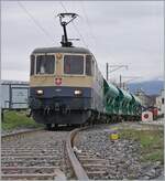 The IRSI/IGE  Rheingold  Re 4/4 II 11387 (Re 421 387-2) in the service of BAM MBC leaves the industrial site near Gland with its gravel train to Apples.

Regarding the photo location: it is on the street that is not closed to train traffic (see geolocation). The train is also standing in front of a signal indicating a stop, as the street is still open to (road) traffic.

March 4, 2024