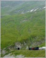 A DFB steam train pictured at the the highest station of Furka Mountain Railway (2160 m above sea level) together with the entry to the 1874 m long summit tunnel on August 1st, 2008.