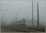 By a heavy fog is entering in the Noiraigue station the TRN local train to Buttes.