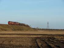 a 2T3116 double-diesel winds its way up to the bridge over the road Tallinn - Narva with a loaded oil train
