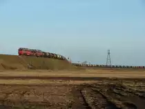 a 2T3116 double-diesel winds its way up to the bridge over the road Tallinn - Narva with a loaded oil train