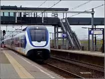 A local train from Roosendaal to Den Haag Centraal is arriving in Lage Zwaluwe on March 10th, 2011.
