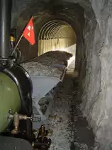 2 ft gauge steam engine  Liseli  (Jung No 1693, built 1911) in service on the high alpin panoramic railway of  Parc d'Attractions du Chatelard (VS)  in Switzerland. Traversing tunnel No 4 with a ballast train. To see in the background is a gallery; the sun light gives an imput to the scenery. The picture was taken from the locomotive platform running backwards to the station  Pied du barrage ; it is clear, walking to foot trough the tunnels is very dangerous and because of that strong forbidden. 21 Oct 2007