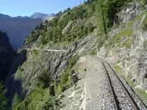 2 ft gauge steam engine  Liseli  (Jung No 1693, built 1911) in service on the high alpin panoramic railway of  Parc d'Attractions du Chatelard (VS)  in Switzerland. View from the last passenger coach backwards in direction to the immense dam of  Lac d'Emosson . The dam's shadow will  eat  in few time the station  Pied du Barrage . On both sides the railway line are to see the vertical mountain rocks, because of that it is'n possible to reach the railway lines by footwalk. This photo I loadet up, because the uncomparable scenery on 1'800 metres about sea level is here best to see. 11 Sept 2010